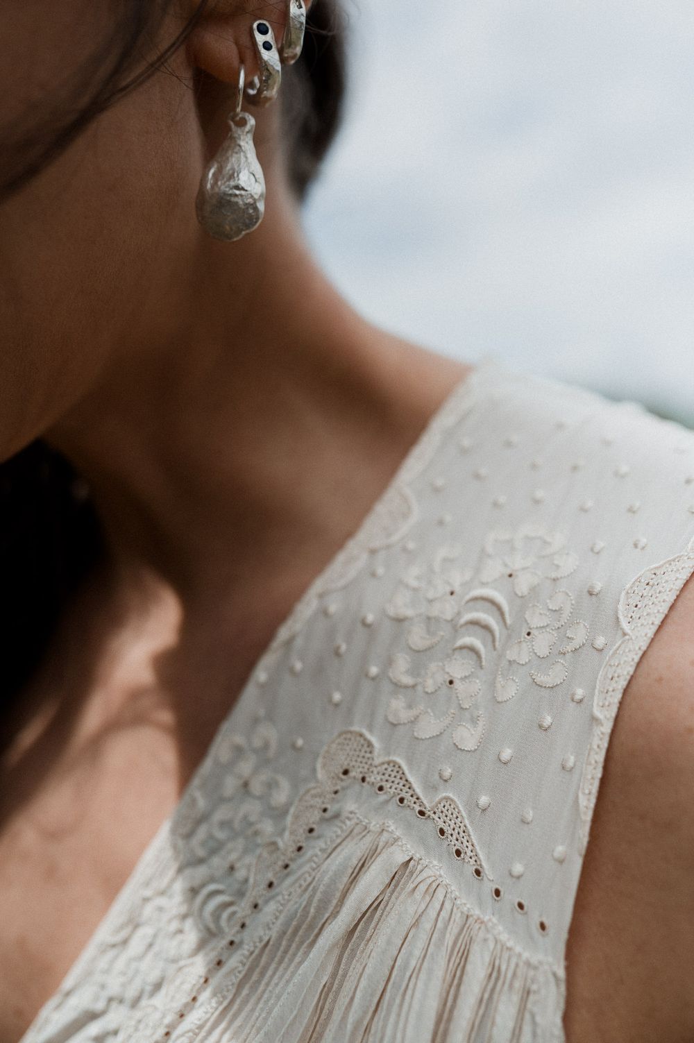 Close-up detail shots of delicate white eyelet lace fabric on a dress with intricate embroidered patterns and textures.