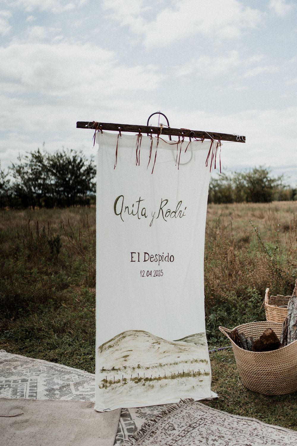 Rustic wedding seating chart display with 'El Dorado' text on white fabric against natural outdoor backdrop.