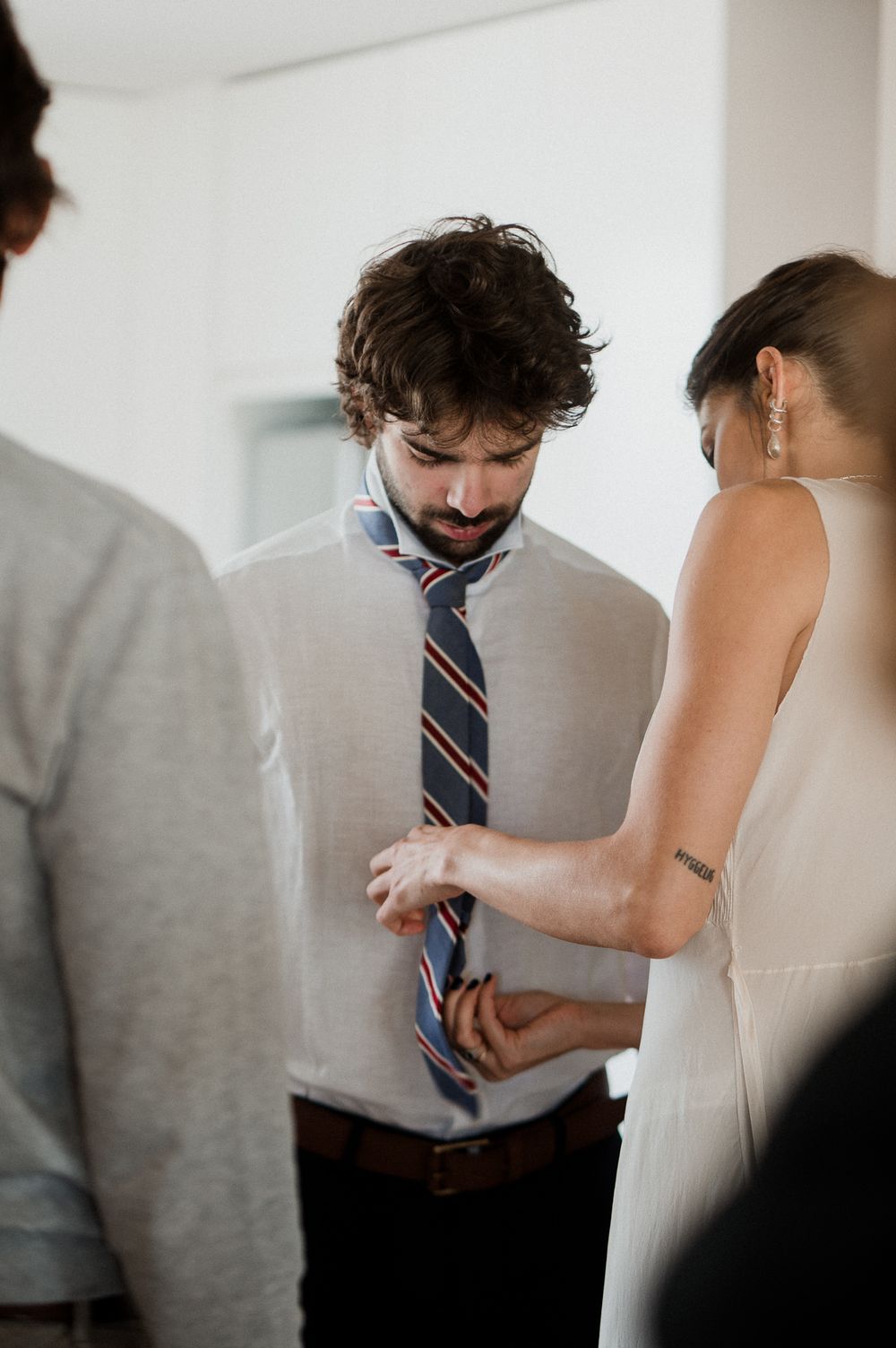A series of photos showing someone adjusting a striped tie against a light colored shirt.