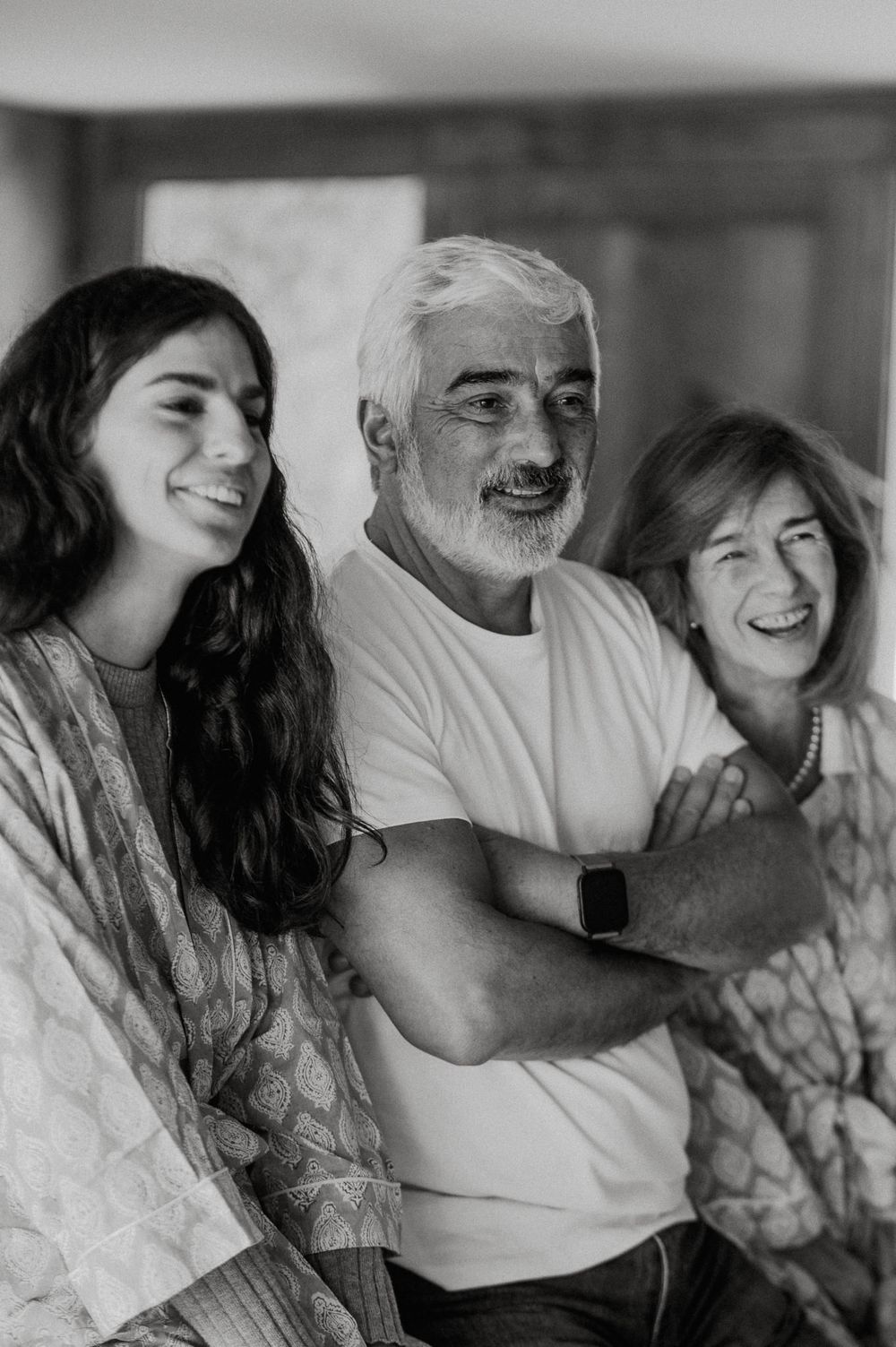 A black and white photo series showing a couple sharing intimate moments and laughter together on a couch.