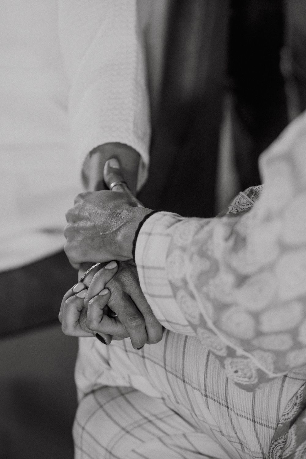 Black and white close-up of hands holding a wrinkled white shirt fabric with subtle pinstripe pattern.