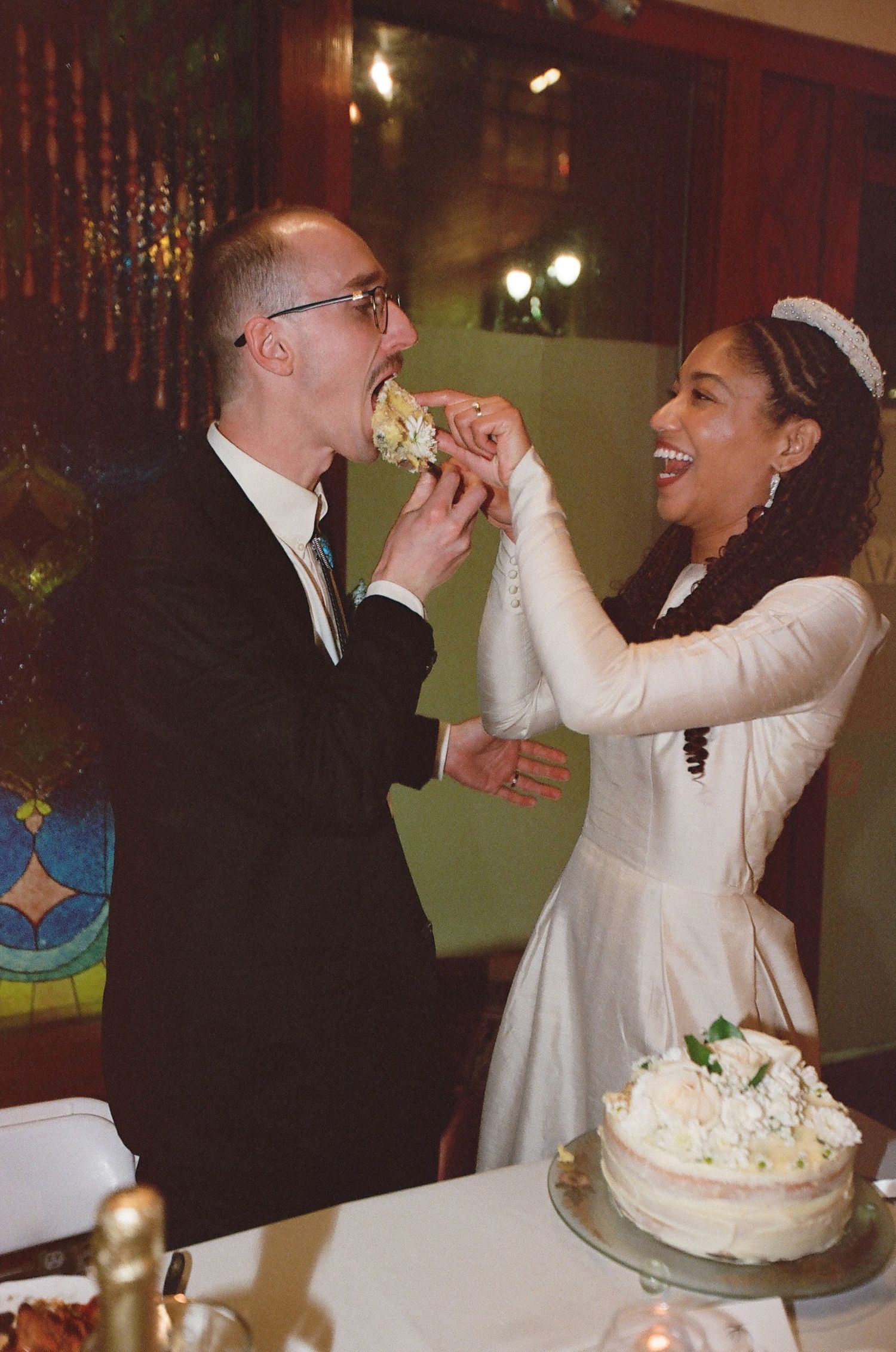 Newlyweds share a playful moment while cutting their wedding cake at the reception.