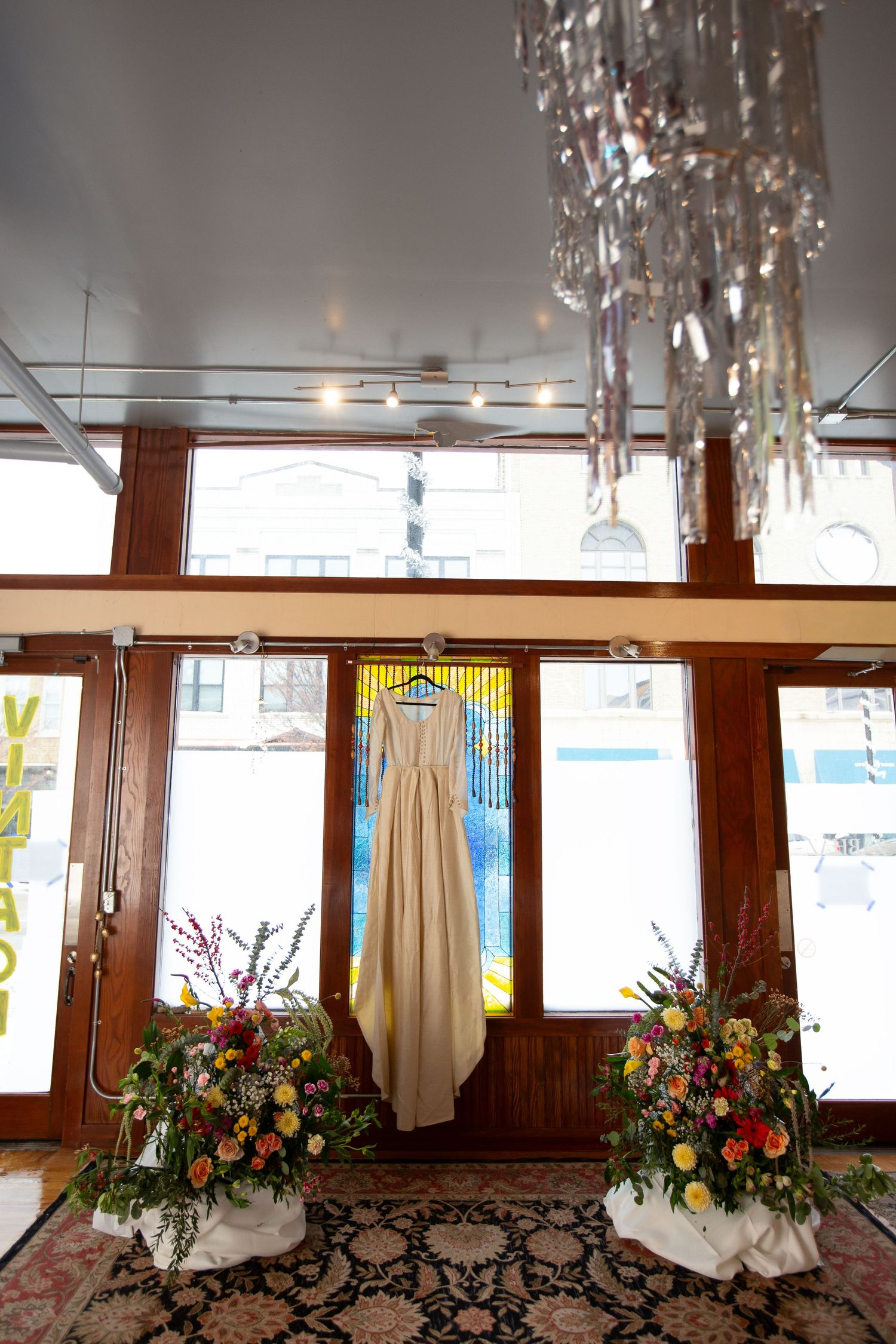 Elegant wedding venue interior with hanging crystal chandeliers and floral arrangements by windows.