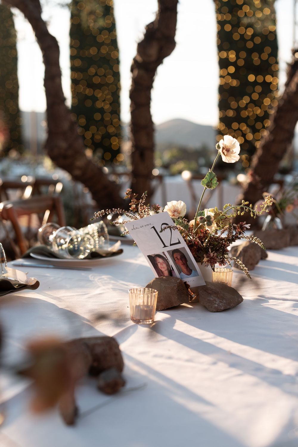 Rustic wedding table decor with brown bottles, twinkling lights, and soft shadows creating a romantic atmosphere.