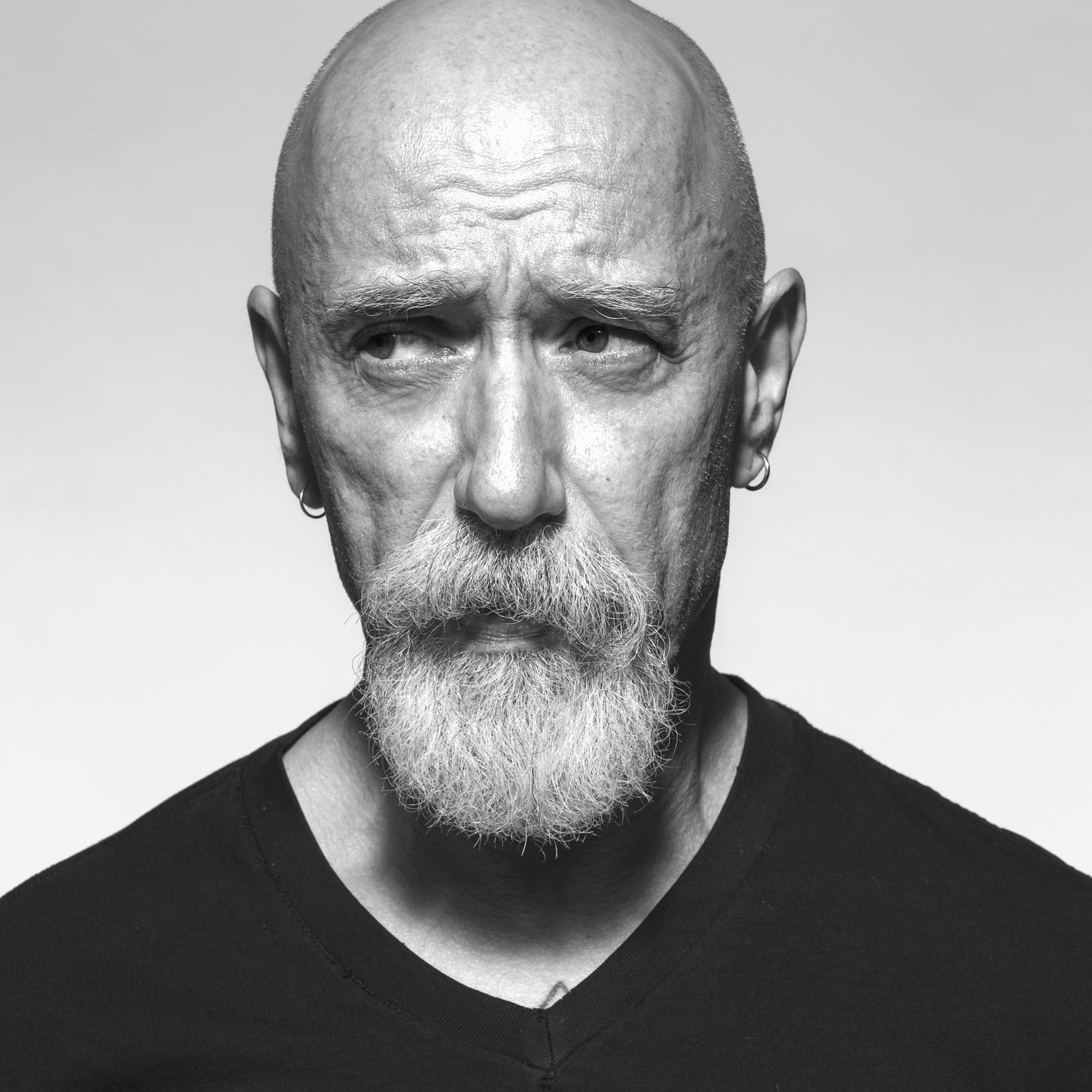 A studio black and white Headshot photograph of  an older man lookiing sideways. Black and white fine art portrait.