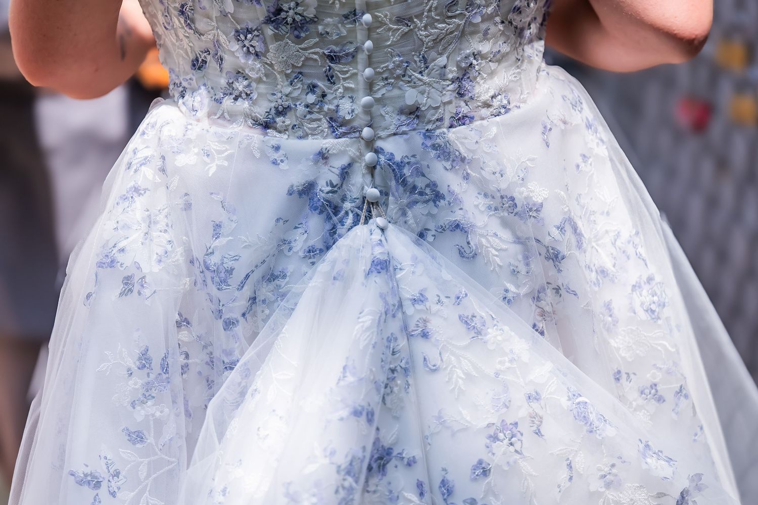 Back view of a white and blue floral ball gown wedding dress with corset lacing and delicate button details.