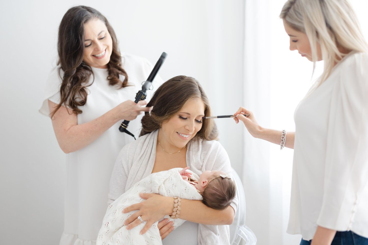 Professional photographer captures tender newborn moments in bright white studio setting.