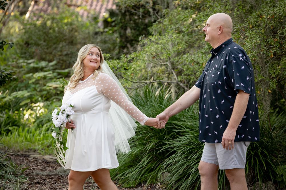 A couple shares a romantic moment together in a lush garden setting during a summer photoshoot.