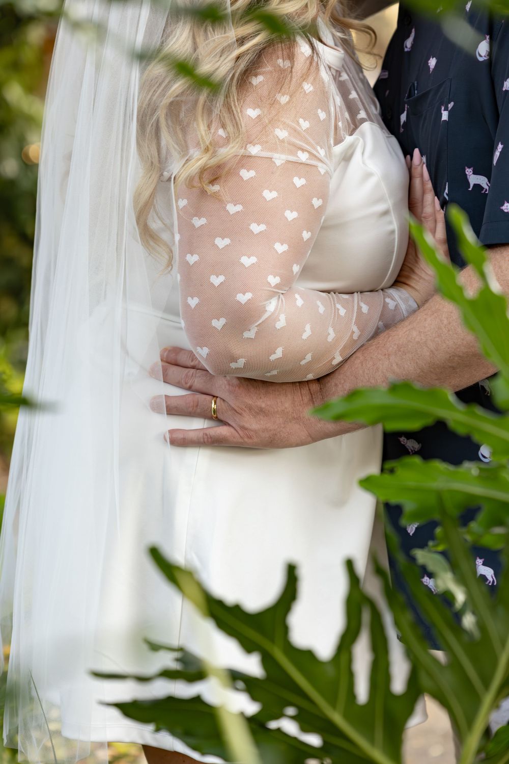 Close-up view of a couple embracing, with delicate white fabric and heart-patterned clothing visible.