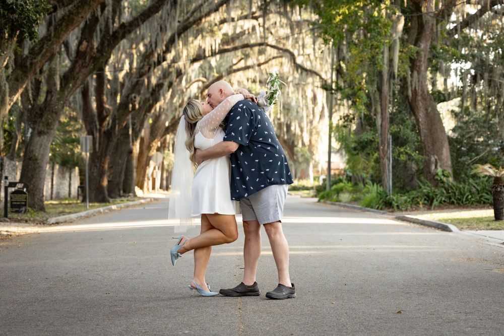 A couple embraces on a tree-lined path during a romantic outdoor photo session at sunset.