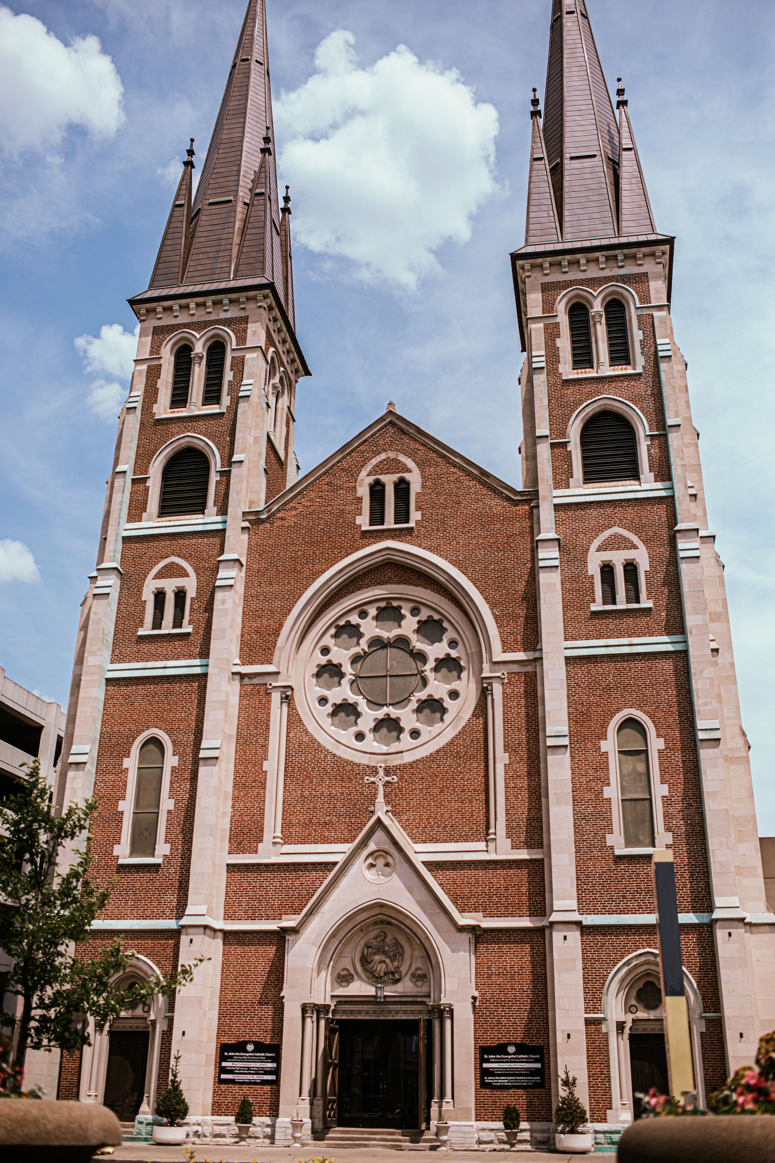 Gothic-style brick church with twin spires and ornate rose window photographed from different angles against blue sky.