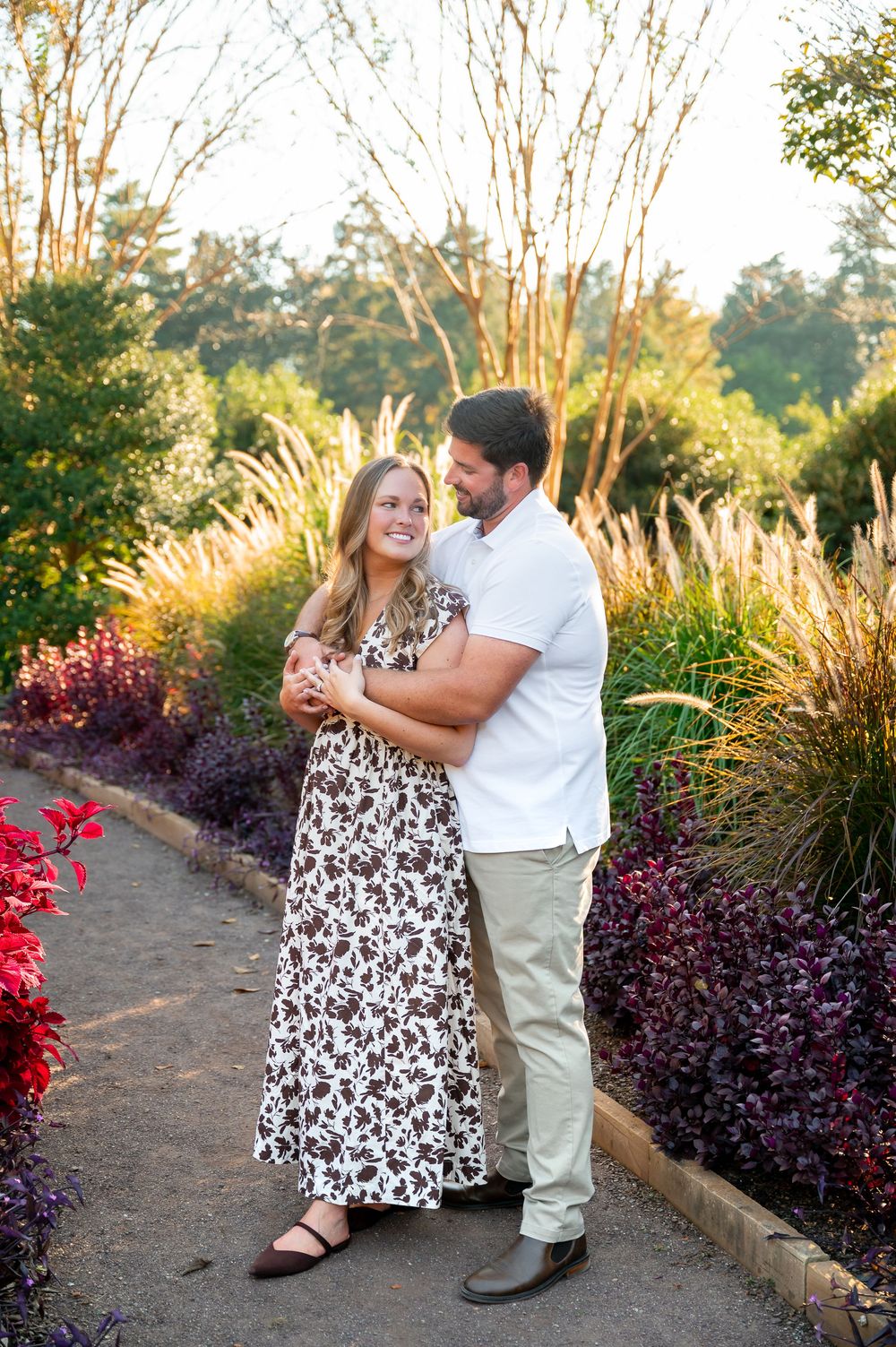 Couple dances and twirls together on garden path lined with ornamental grasses and flowers.