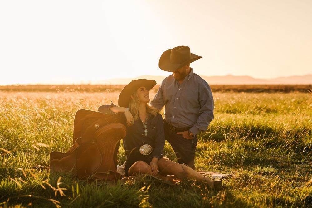 Romantic silhouette of couple sitting together in a golden field during sunset.