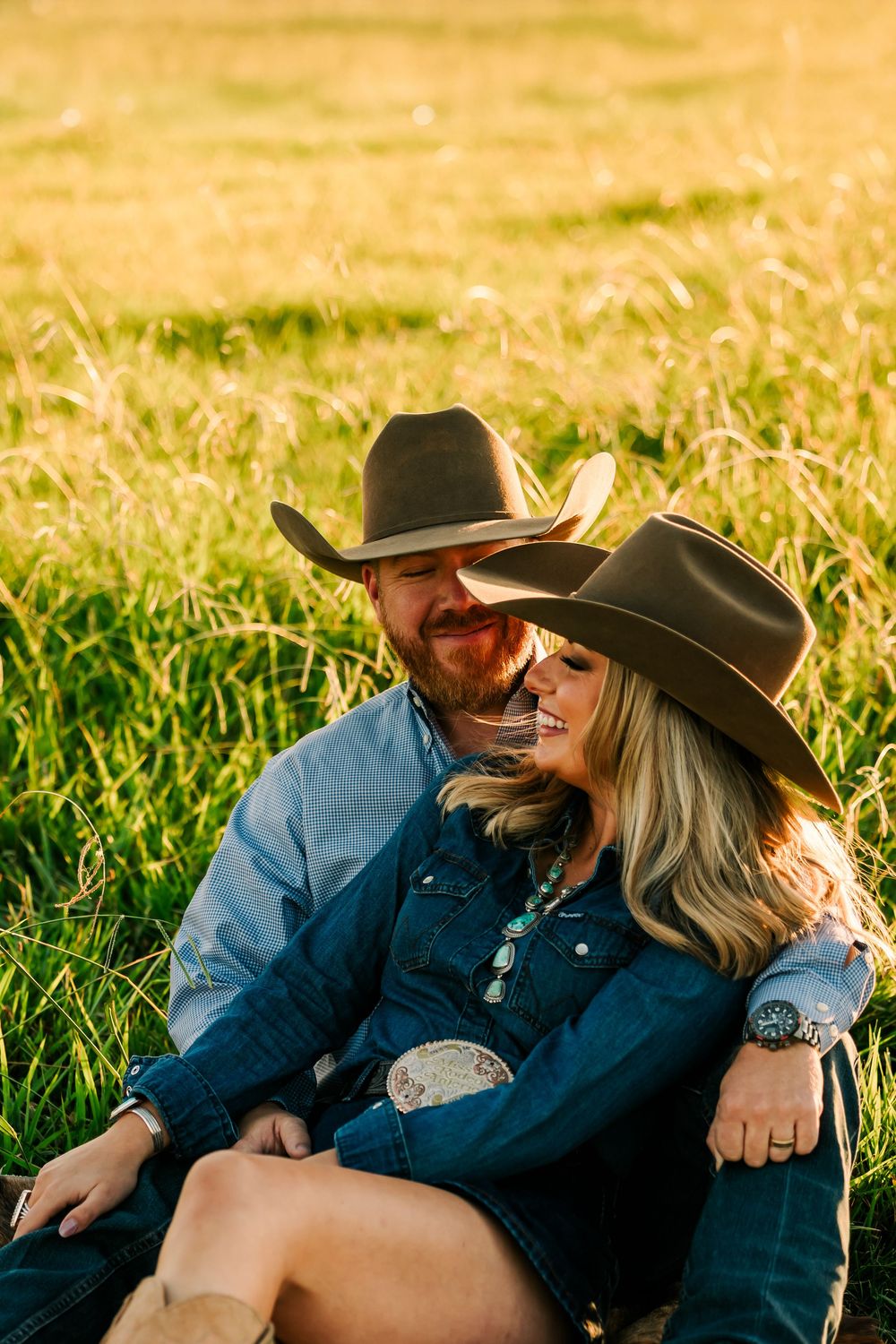 Romantic couple in western attire sharing tender moments in a sunlit meadow at golden hour.