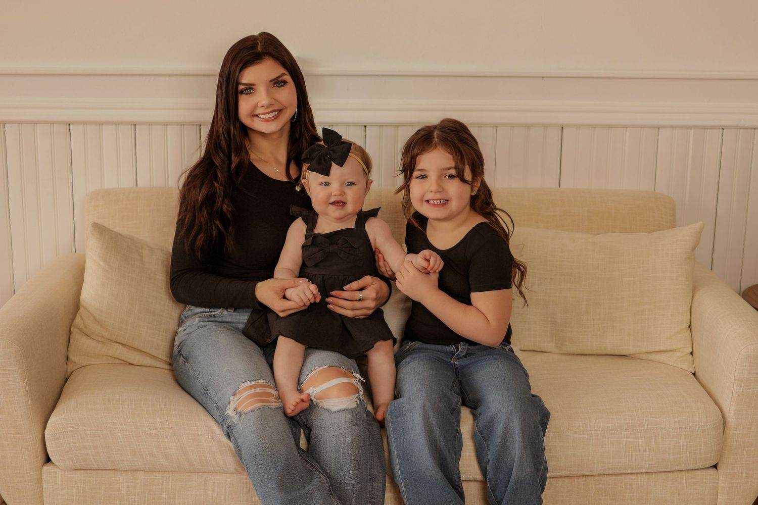 Casual family portrait session on beige couch with natural lighting.
