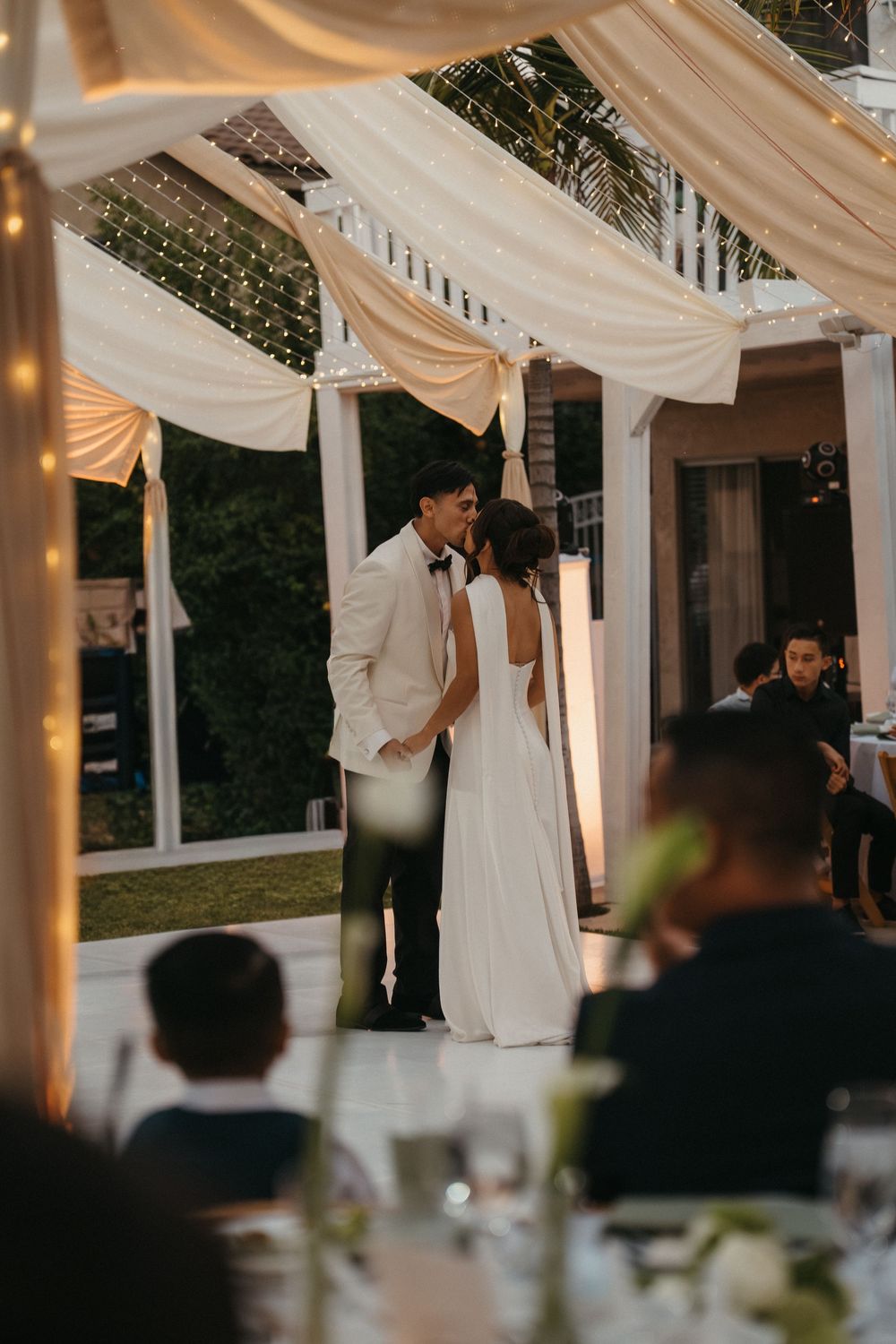 Elegant wedding reception venue with white fabric draping and soft lighting creating a romantic atmosphere.