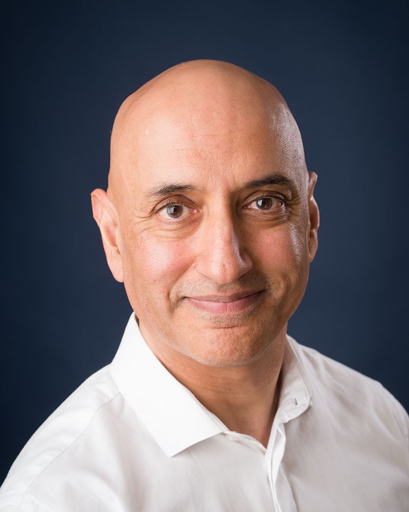 Headshot of a bald man wearing a white shirt, smiling, captured by Abigail's Studio in High Wycombe.
