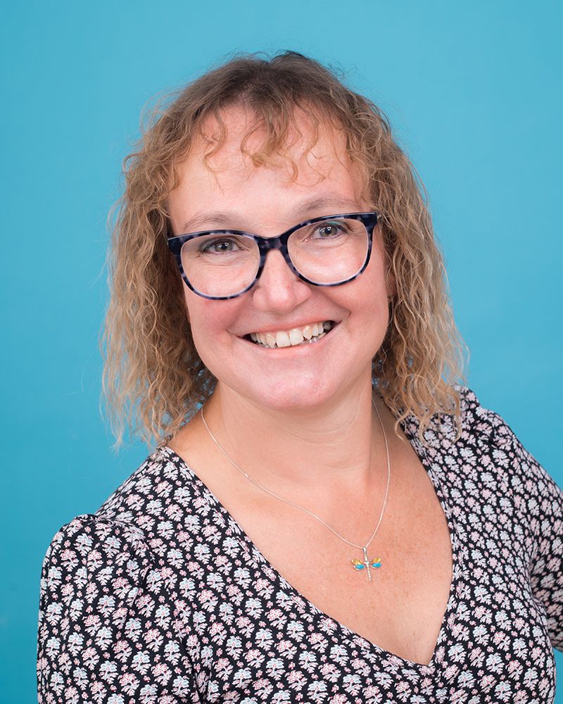 A smiling woman with glasses wearing a floral shirt, captured in a headshot by Abigail's Studio in High Wycombe.