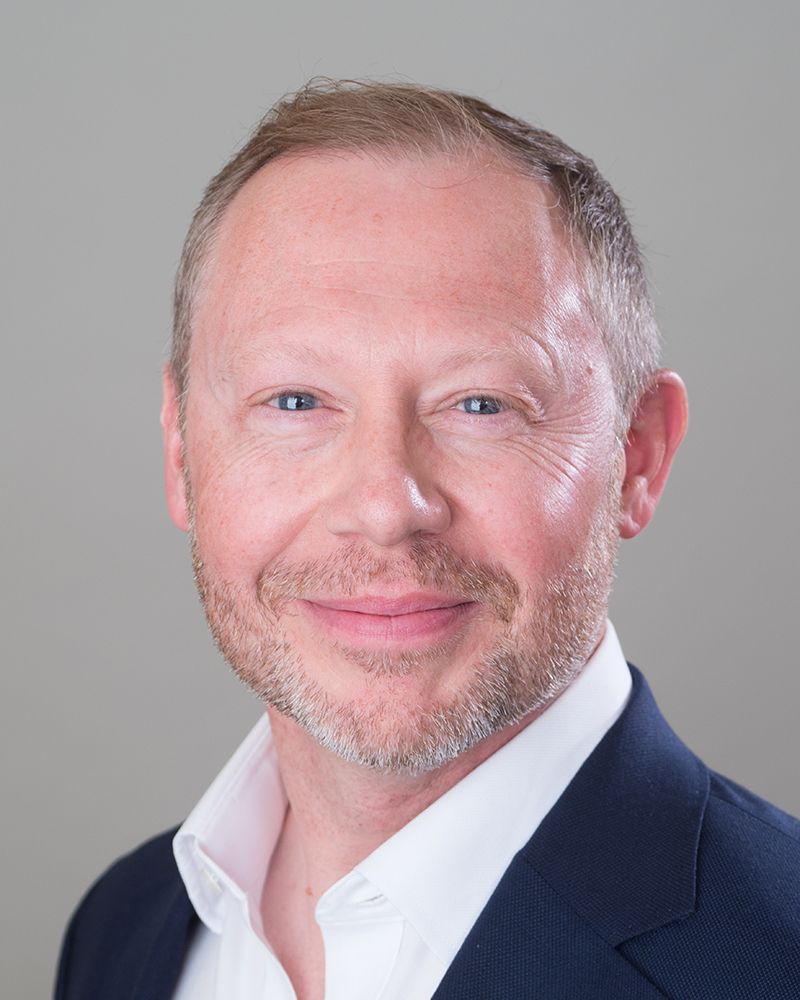 Headshot of a man in a suit and white shirt, smiling warmly, photographed by Abigail's Studio in High Wycombe.