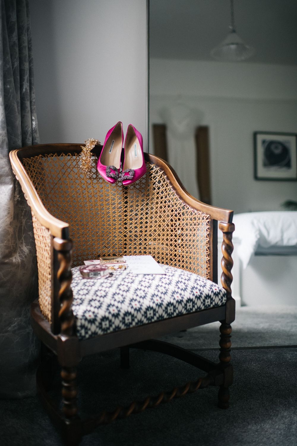 Vintage cane-backed settee with patterned cushions in moody lighting.