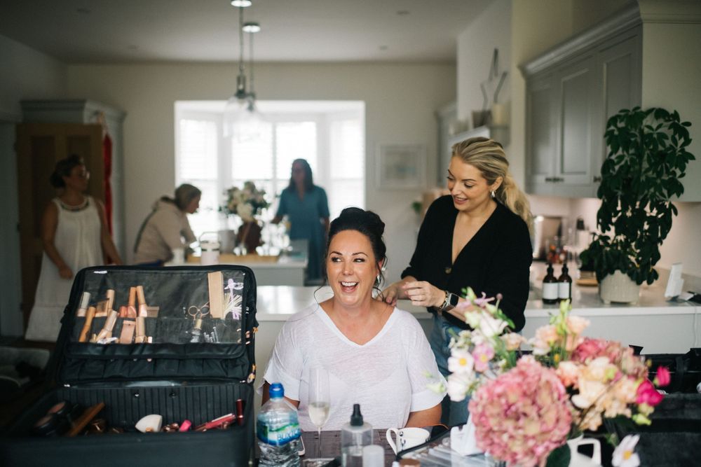 Wedding party getting ready in a bright, modern room with makeup and styling preparations underway.