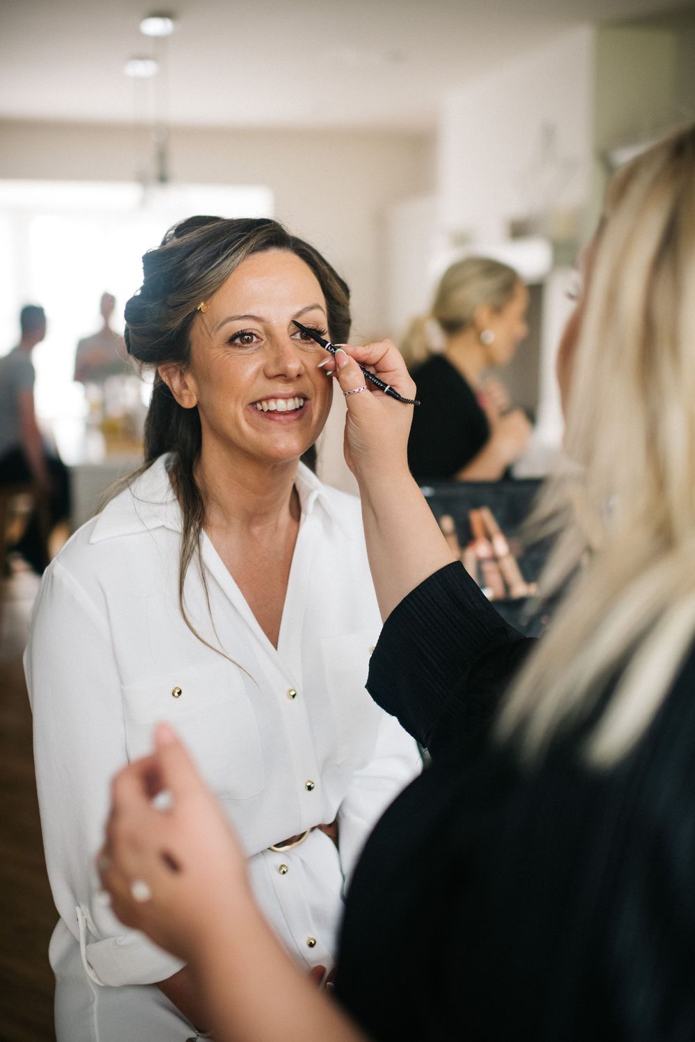 A close-up shot of makeup being applied during wedding preparations in a bright indoor setting.