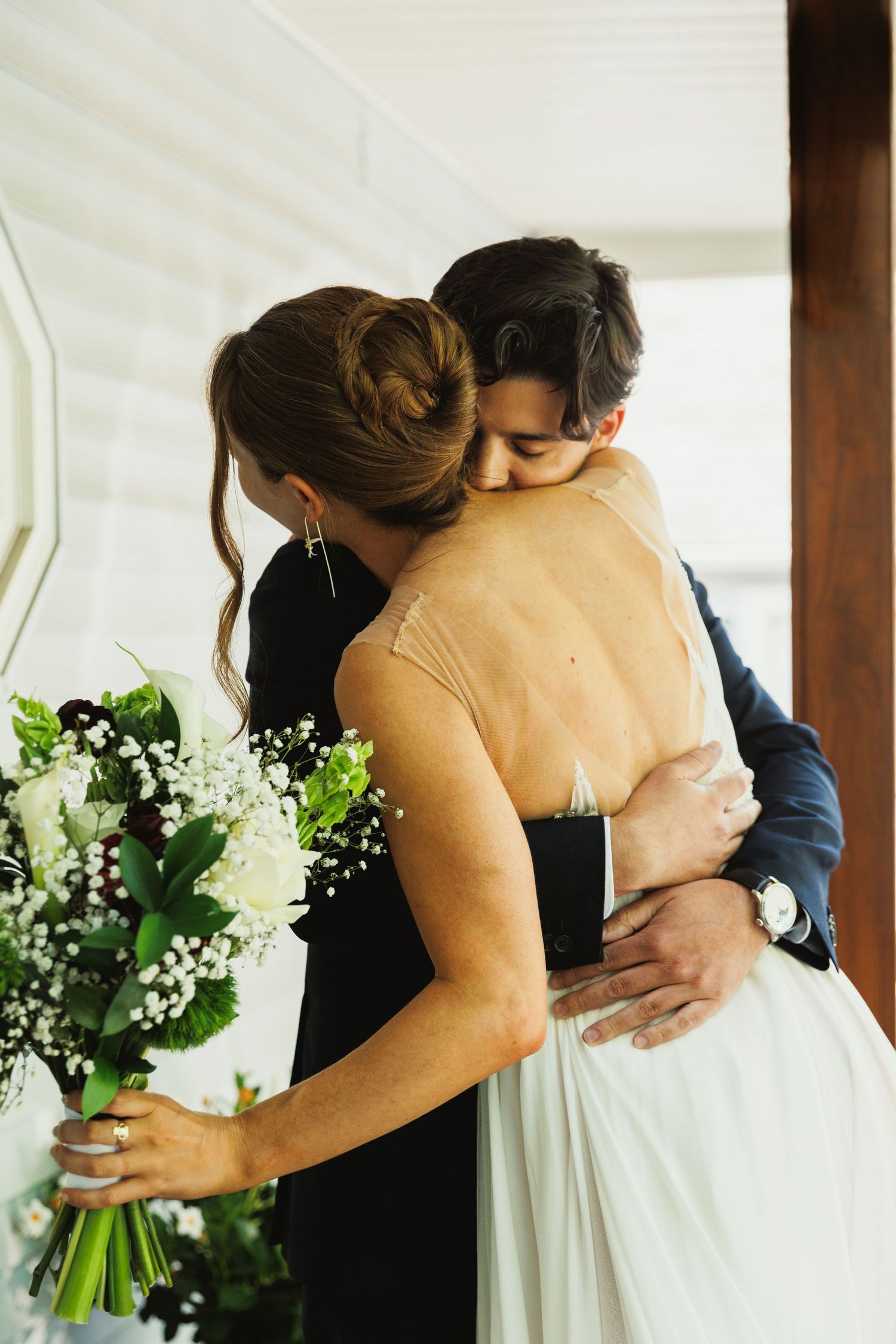 A tender embrace between a couple during their first look moment on a porch.