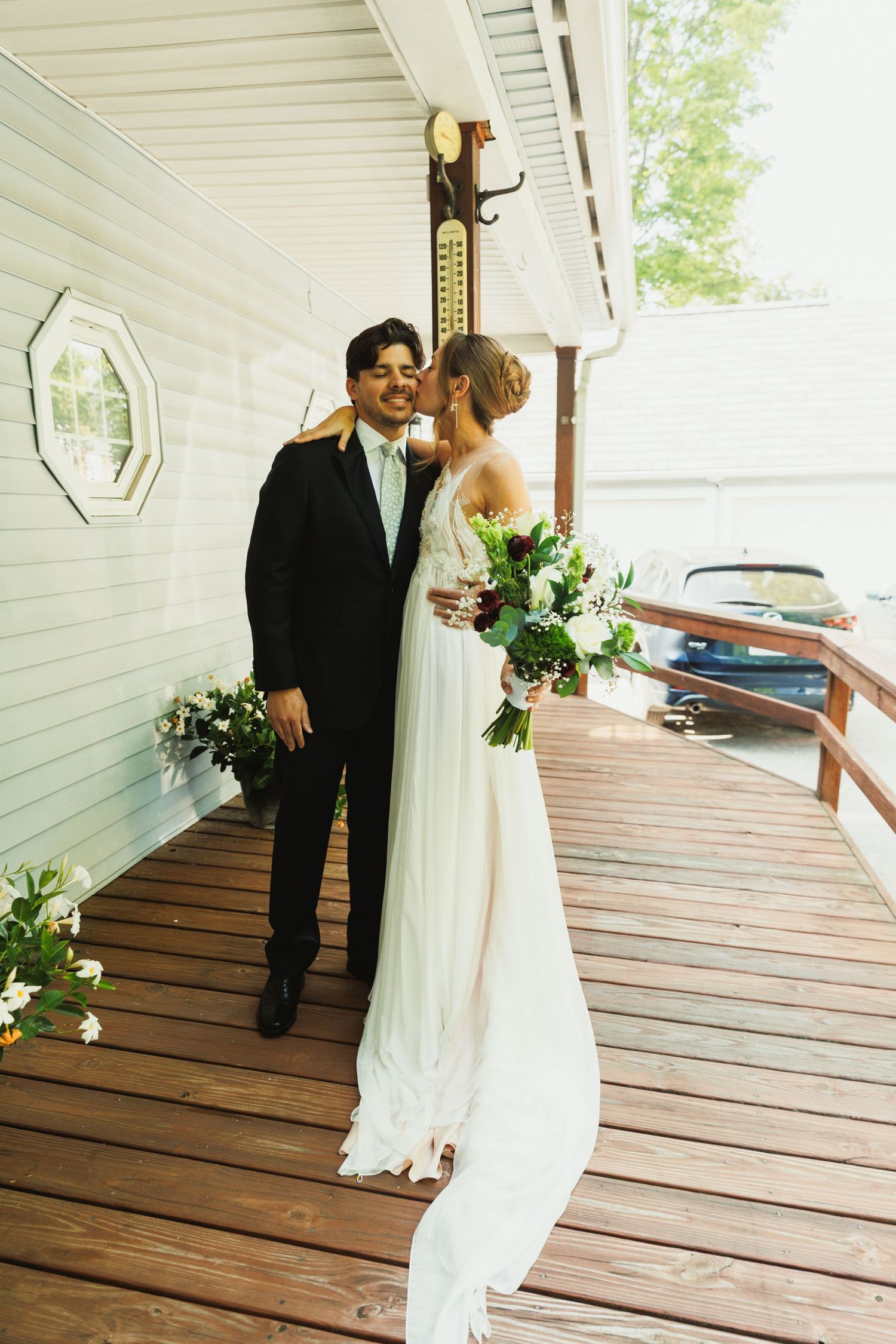 A couple shares an intimate moment on a wooden deck during their first look.