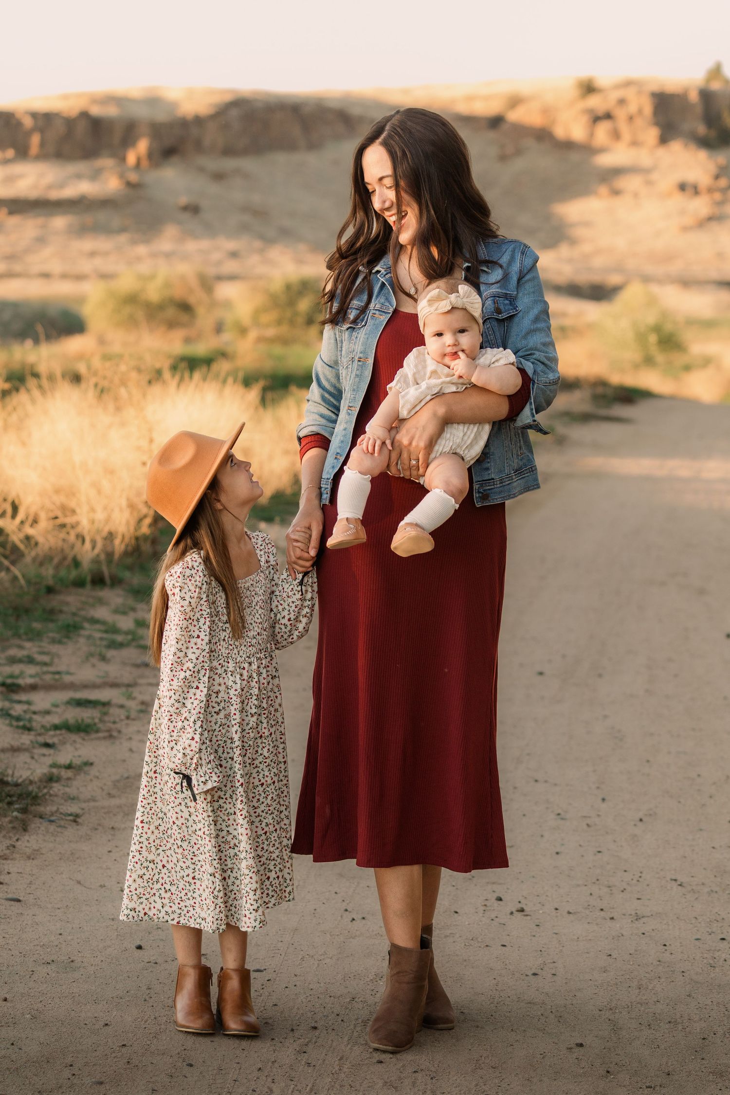 A family enjoys a candid moment together in a sunlit field during golden hour.