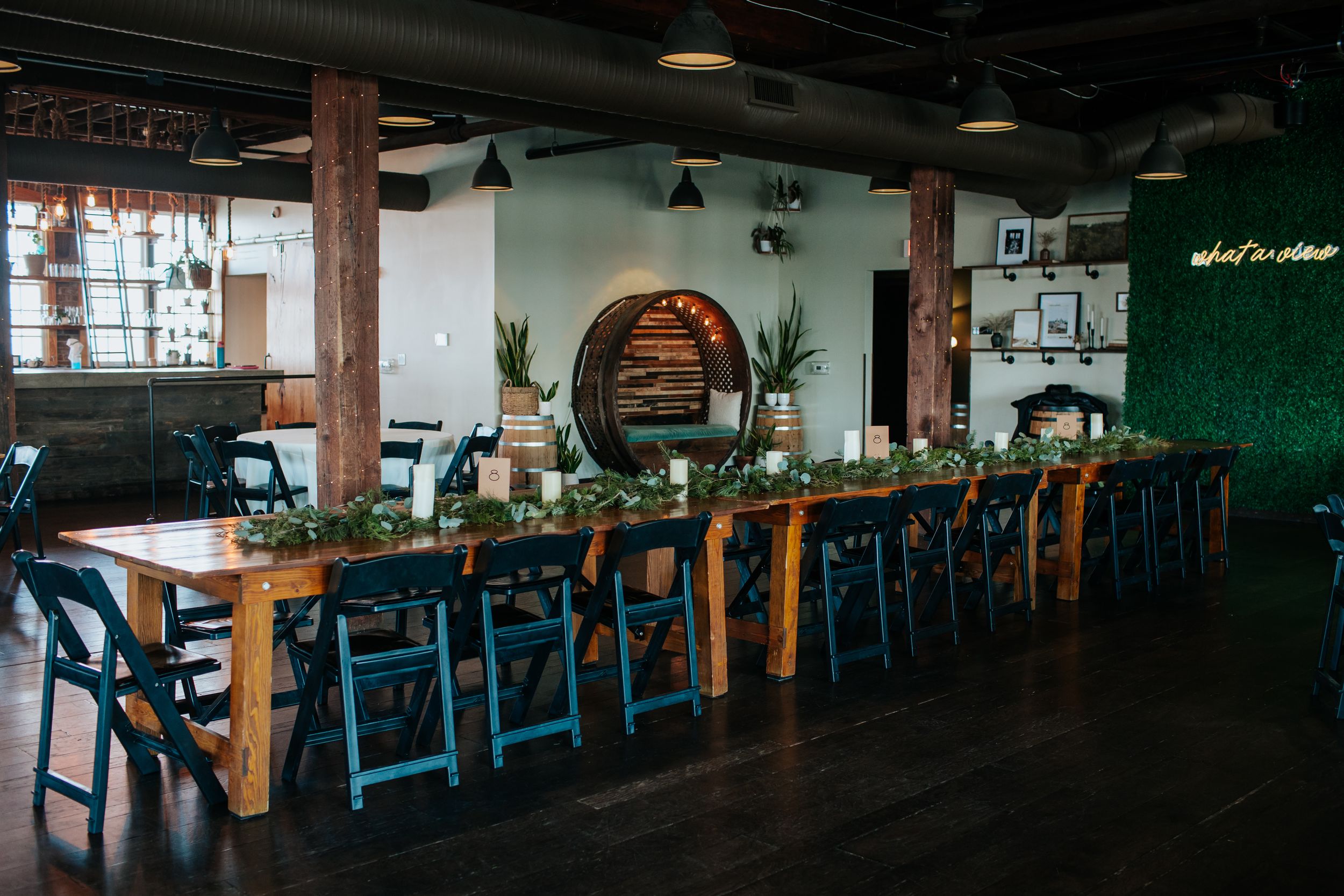 Modern coworking space with wooden tables, blue chairs, and industrial lighting in an open floor plan layout.