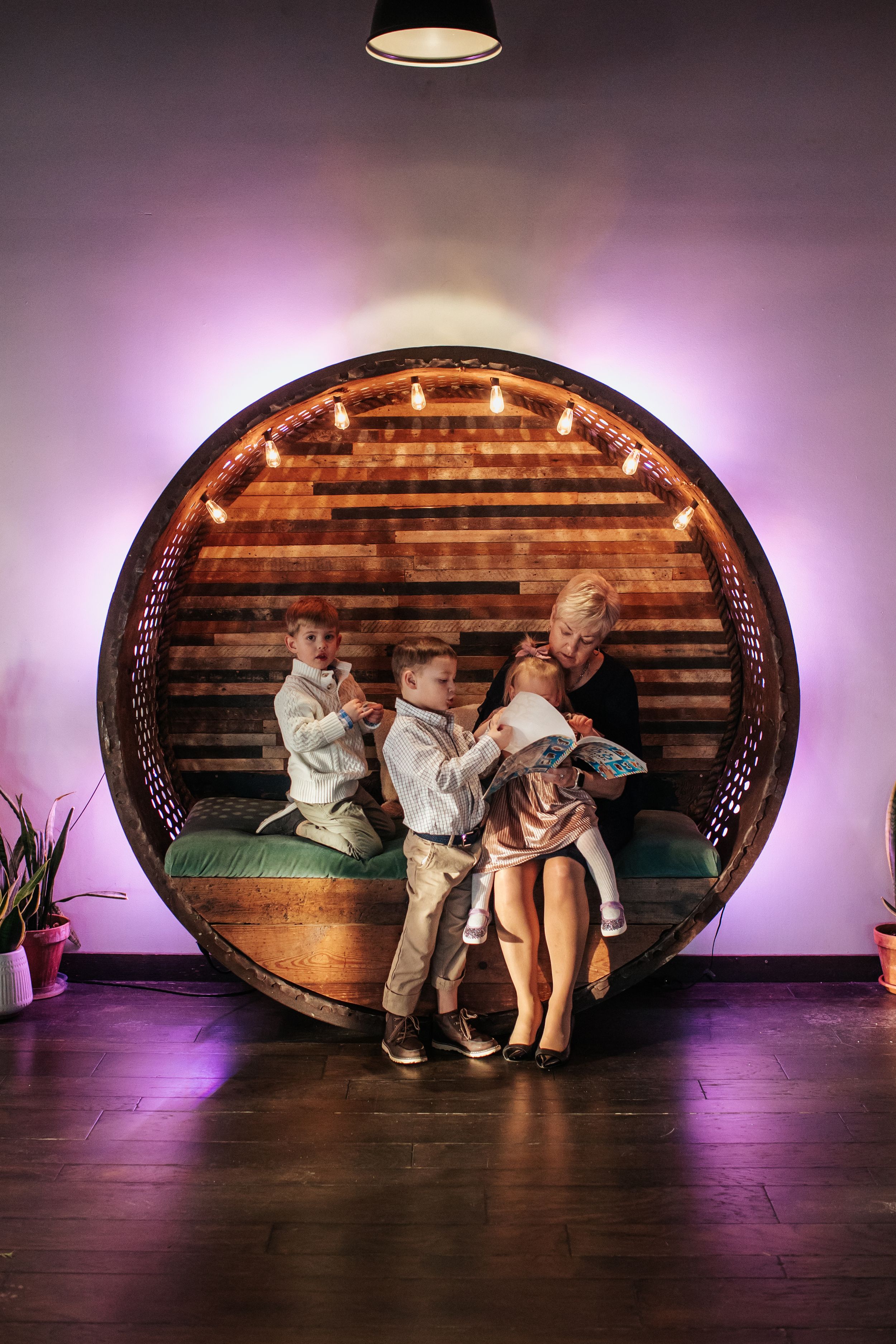 Decorative circular wooden barrel wall display with string lights and purple ambient lighting in an event space.