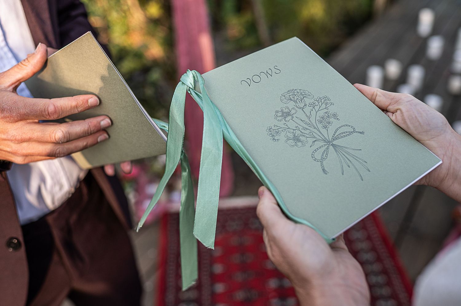 Hands holding green wedding vows booklet