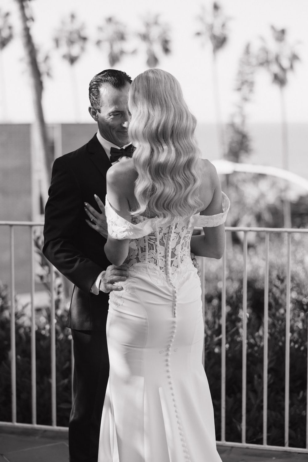 A couple shares an intimate moment on their wedding day in elegant black and white formal attire.