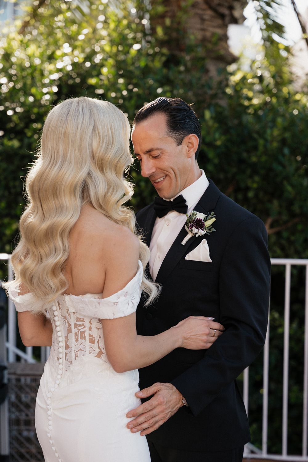 A romantic first look moment between a bride in white and groom in black tuxedo on their wedding day.