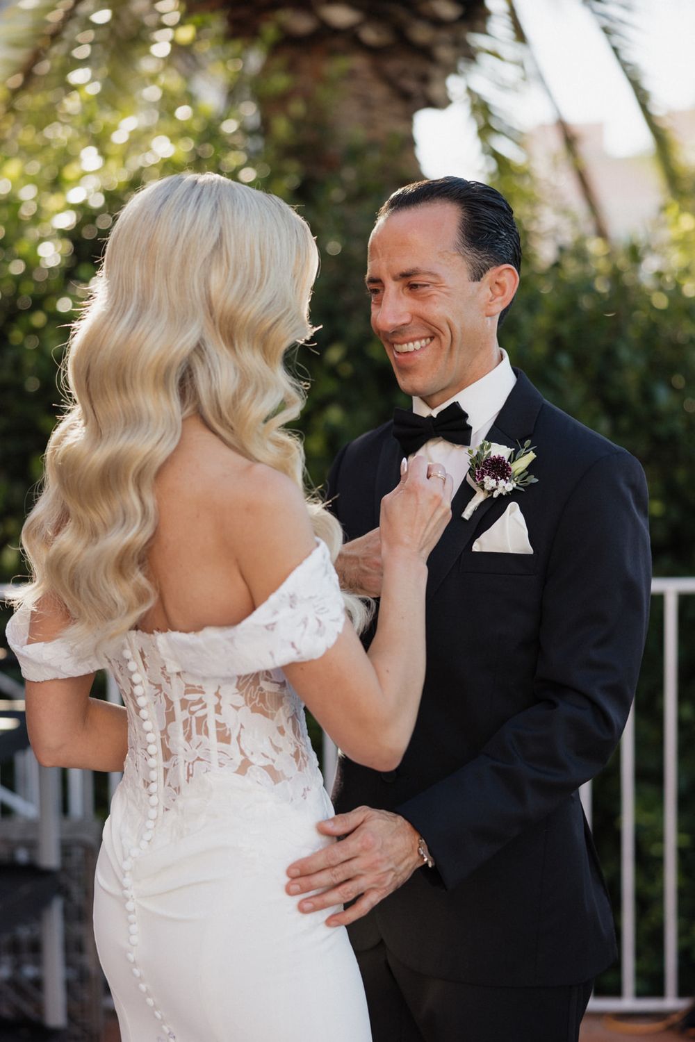 A romantic moment between newlyweds as they share their first look, with the bride in a lace gown and groom in classic tuxedo.