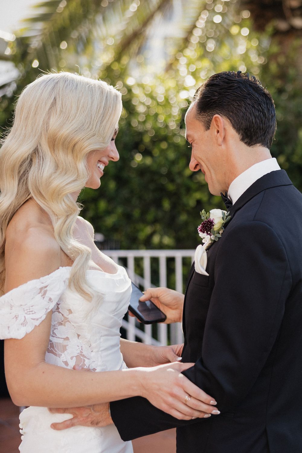 Joyful wedding couple sharing a tender moment against a sunlit tropical garden backdrop.