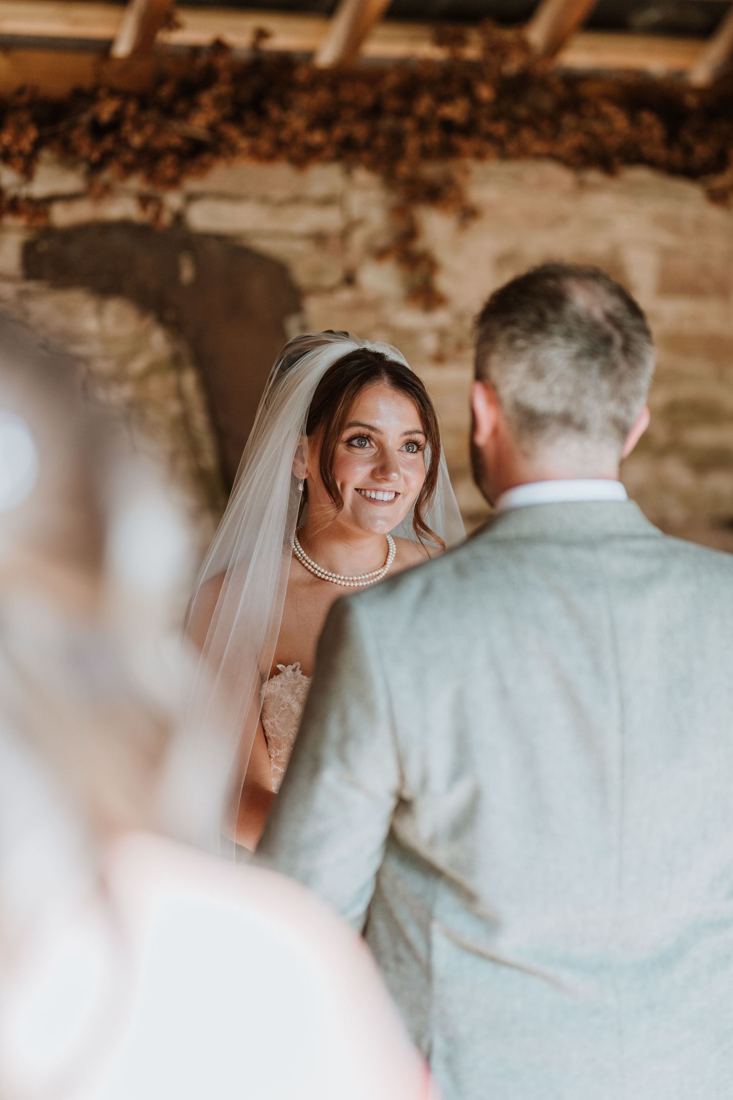 A couple exchanges vows during an intimate rustic wedding ceremony under wooden beams at Lyde Court, Hereford.