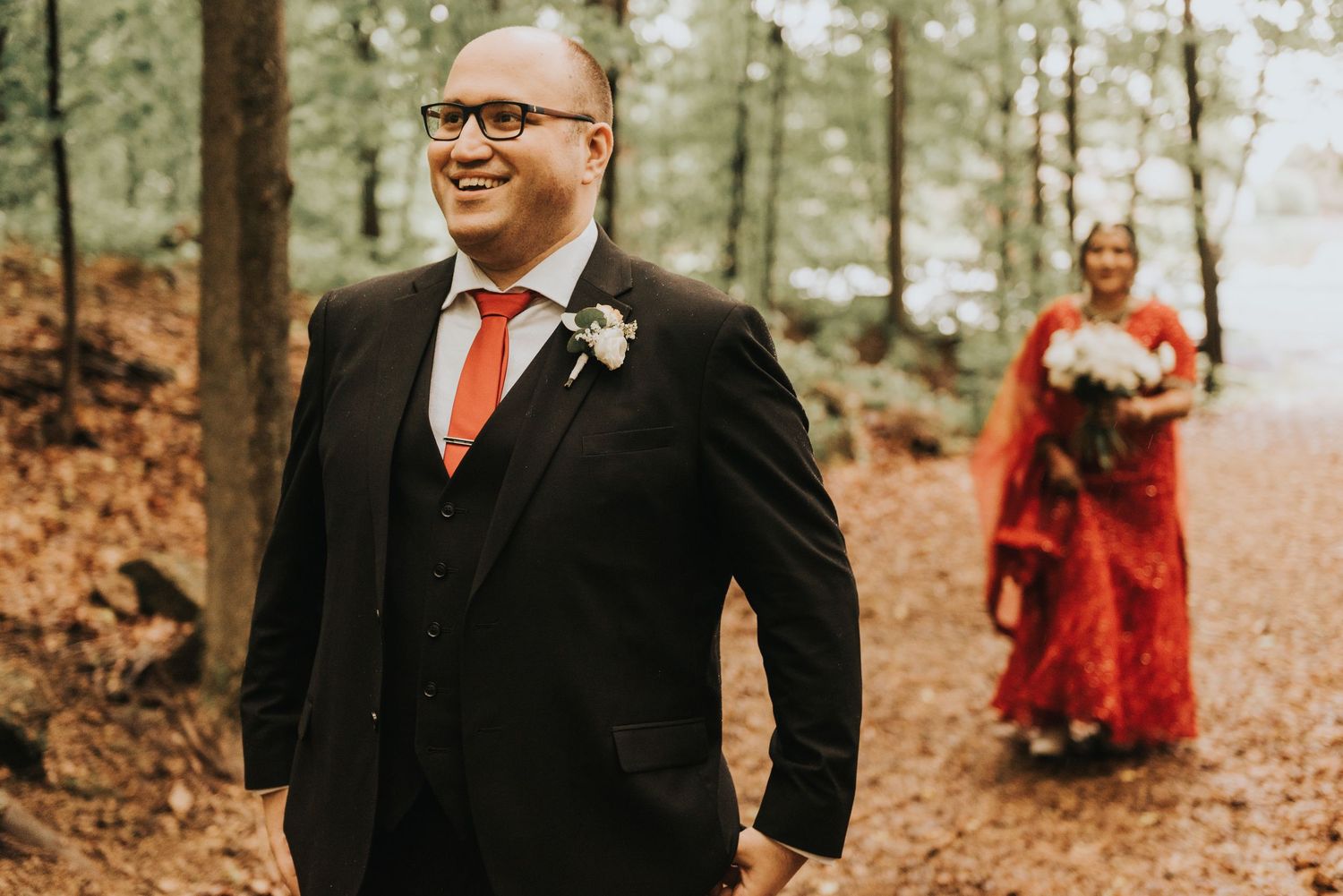 A couple shares a joyful moment in an autumn forest setting with warm lighting and fallen leaves.