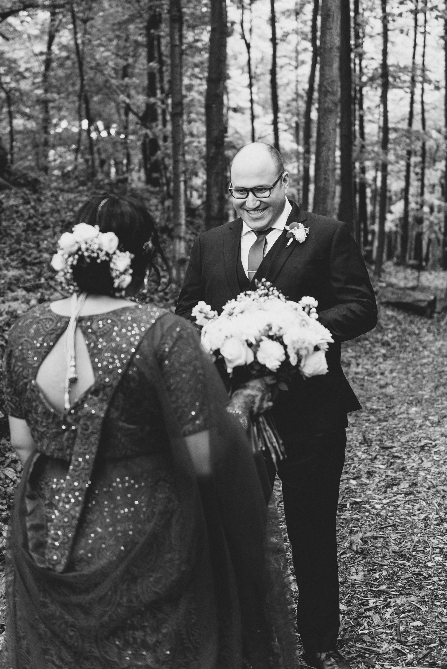 A romantic woodland wedding photoshoot featuring a couple in black and white with white floral bouquet.
