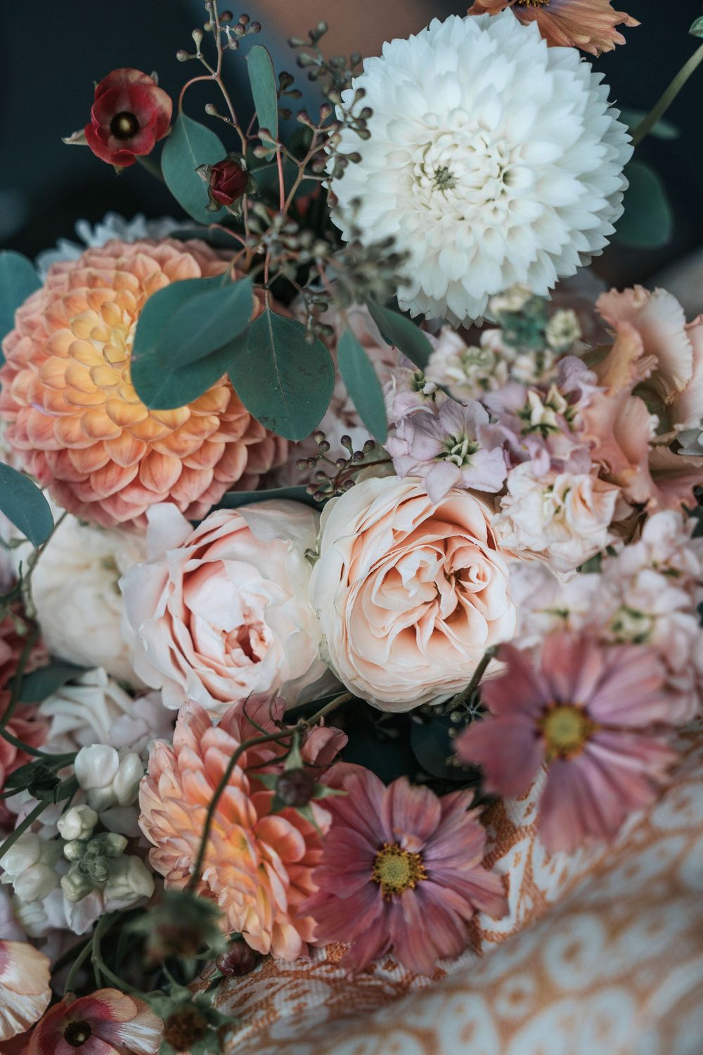 Close-up of autumn wedding flowers in soft peach, blush and cream tones, featuring dahlias and roses styled for a coastal wedding editorial