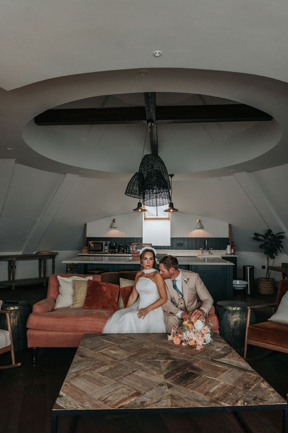 Bride and groom seated together in the Penthouse suite at Gara Rock Hotel during a styled wedding shoot, showcasing warm interiors, natural