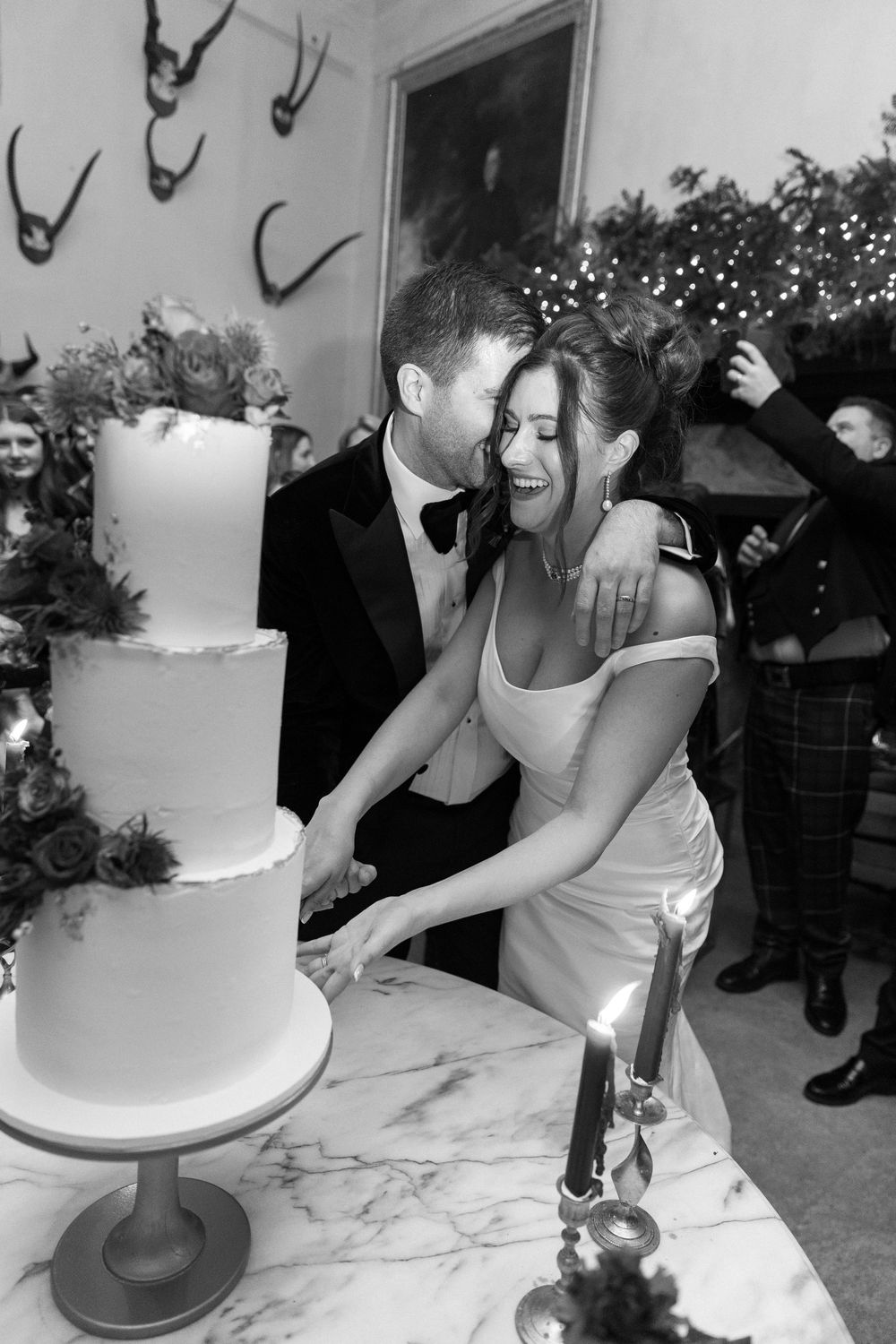 A sequence of photos showing a wedding cake being assembled and decorated on a white marble surface.