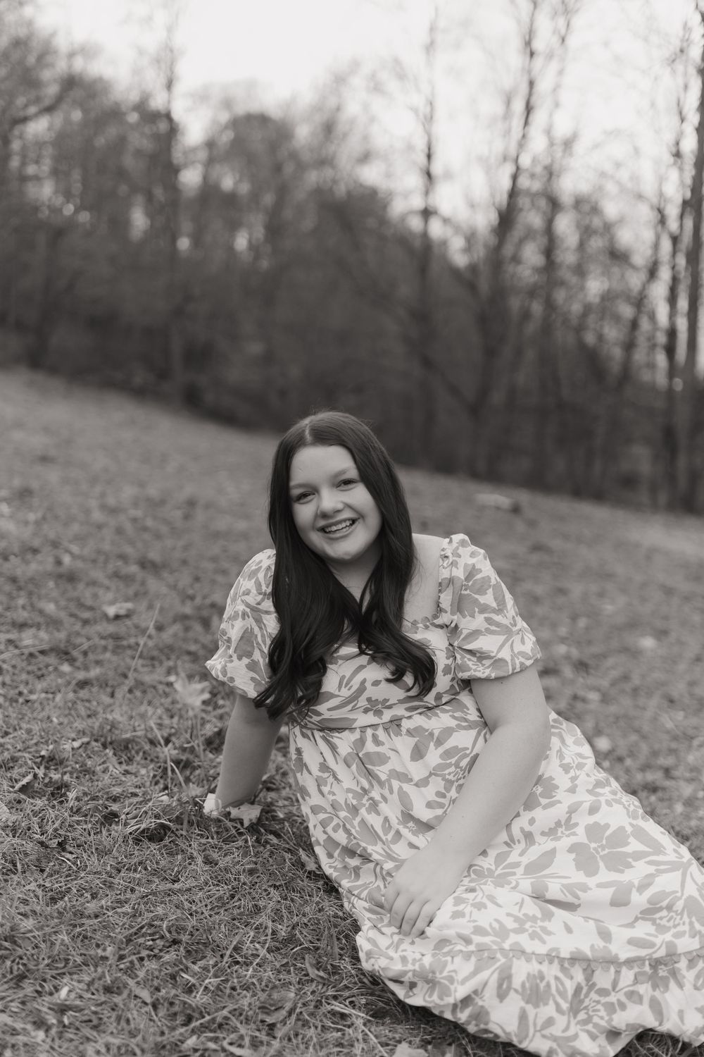 A series of black and white photos showing someone in a floral dress lying on grassy ground.