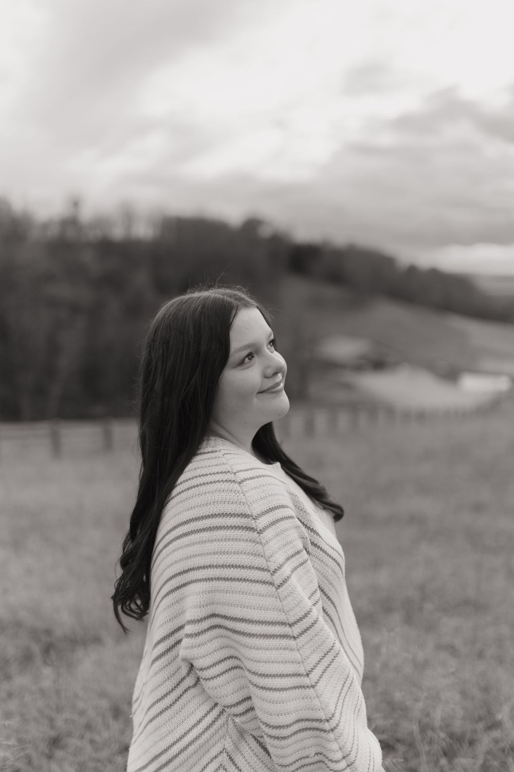 A person in a striped sweater stands in a field looking upward in black and white.