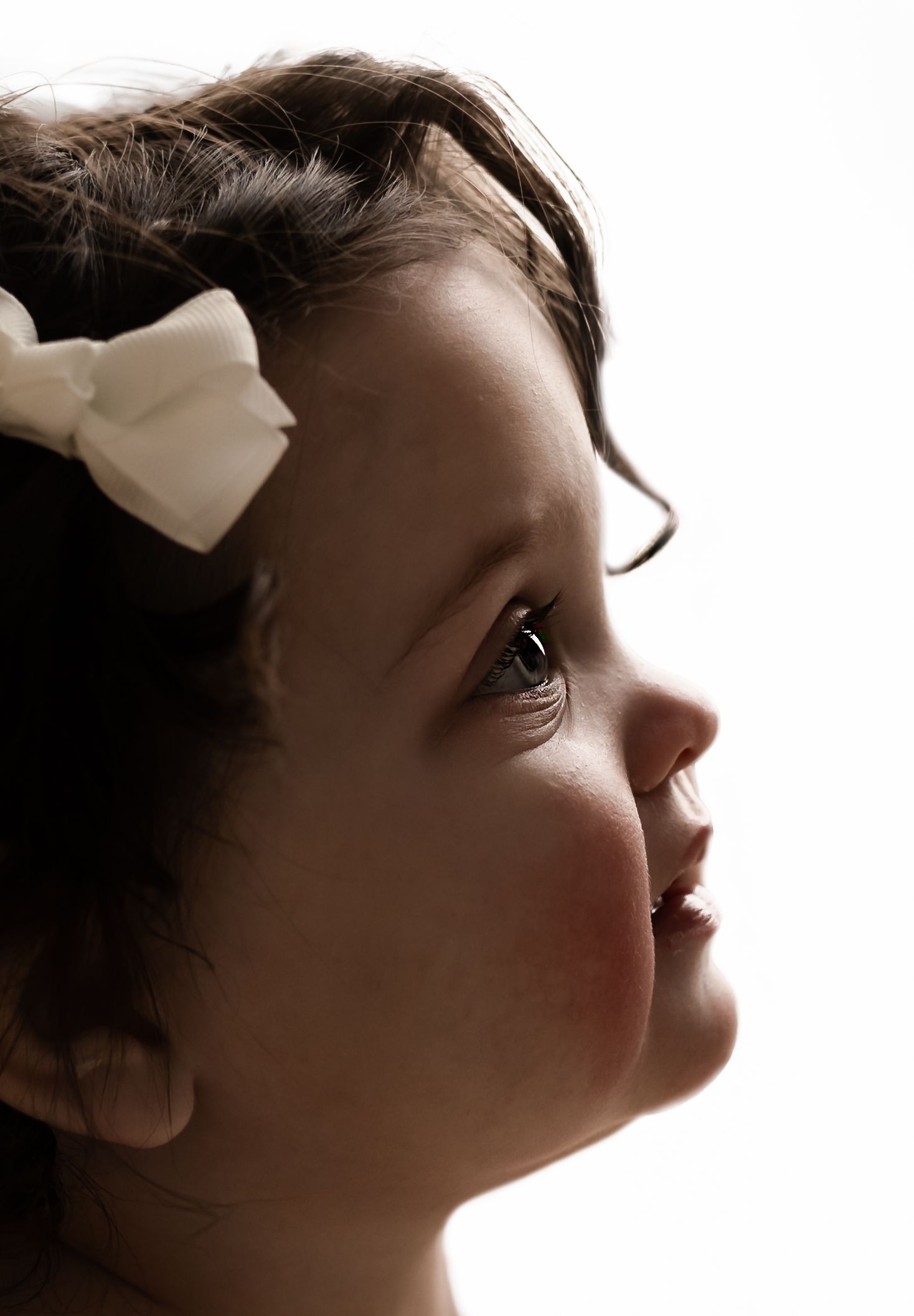 Warm backlit side profile image of a beautiful dark-haired, blue eyed baby girl, captured by Charlottesville newborn photographer.
