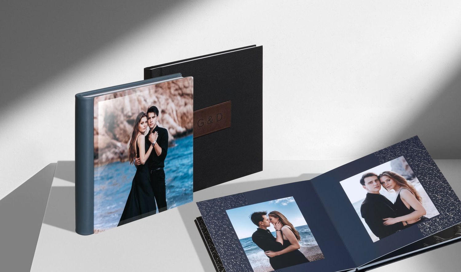 Sleek black leather notebook with gold lettering displayed on various textured backgrounds and surfaces.