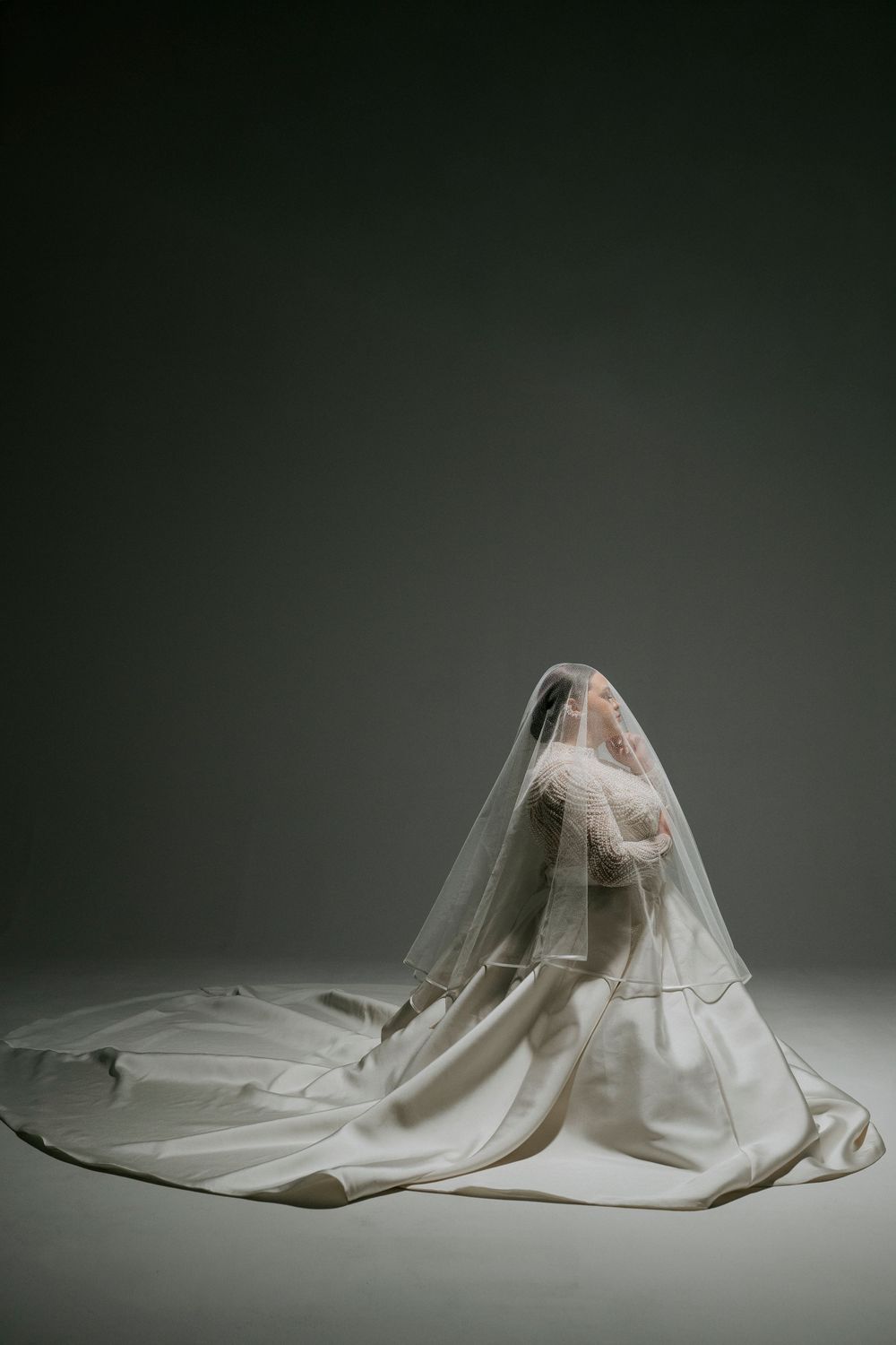 A series of white fabric sculptures resembling draped cloth forms arranged in a minimalist sequence against a dark background.