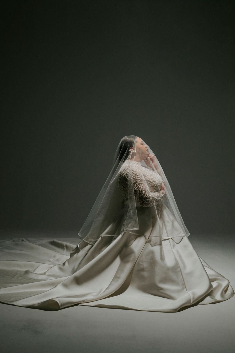 A series of artistic photographs showing a figure draped in flowing white fabric creating dramatic sculptural forms.