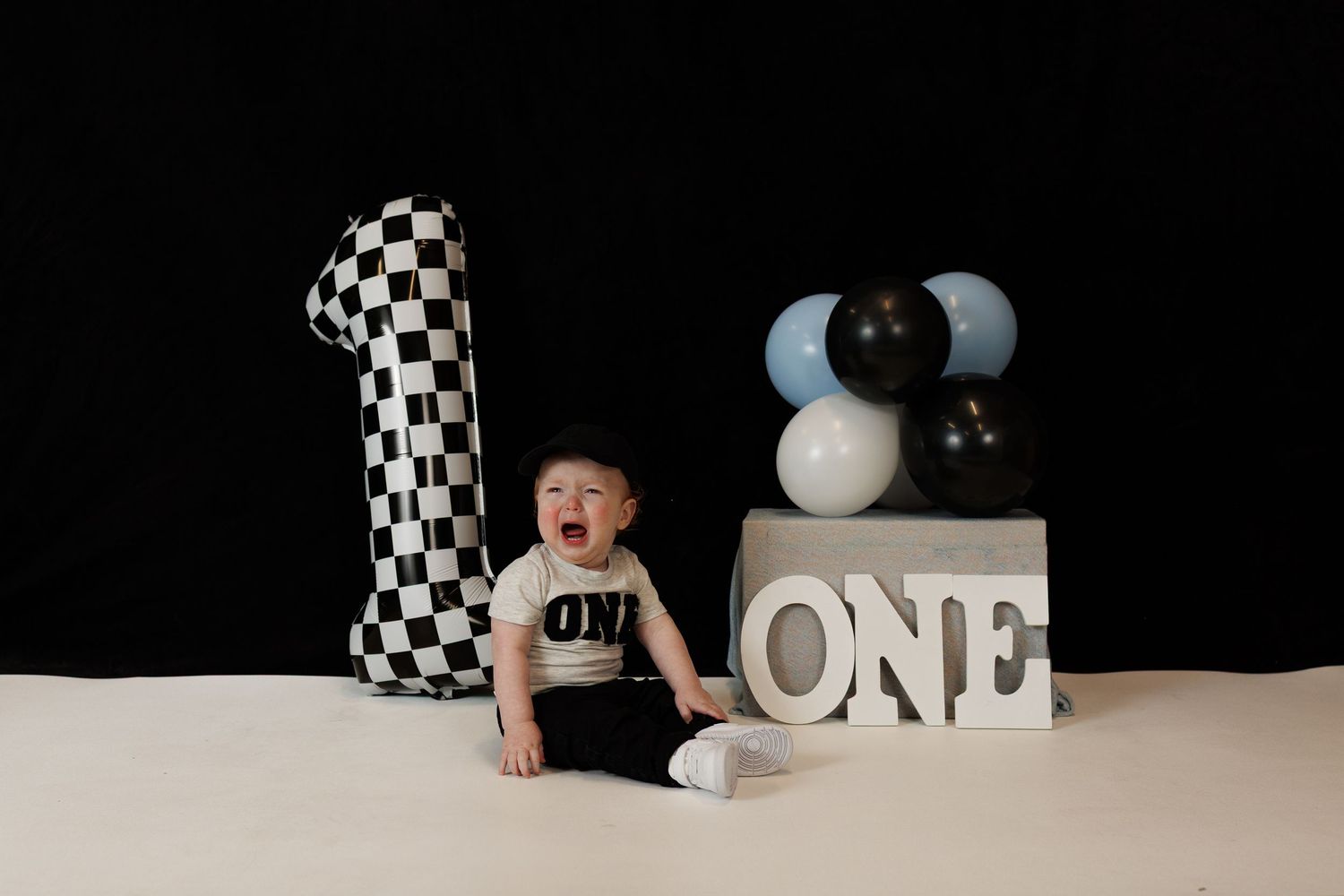 A black and white checkered themed cake smash photo session for a one year old baby's milestone celebration.