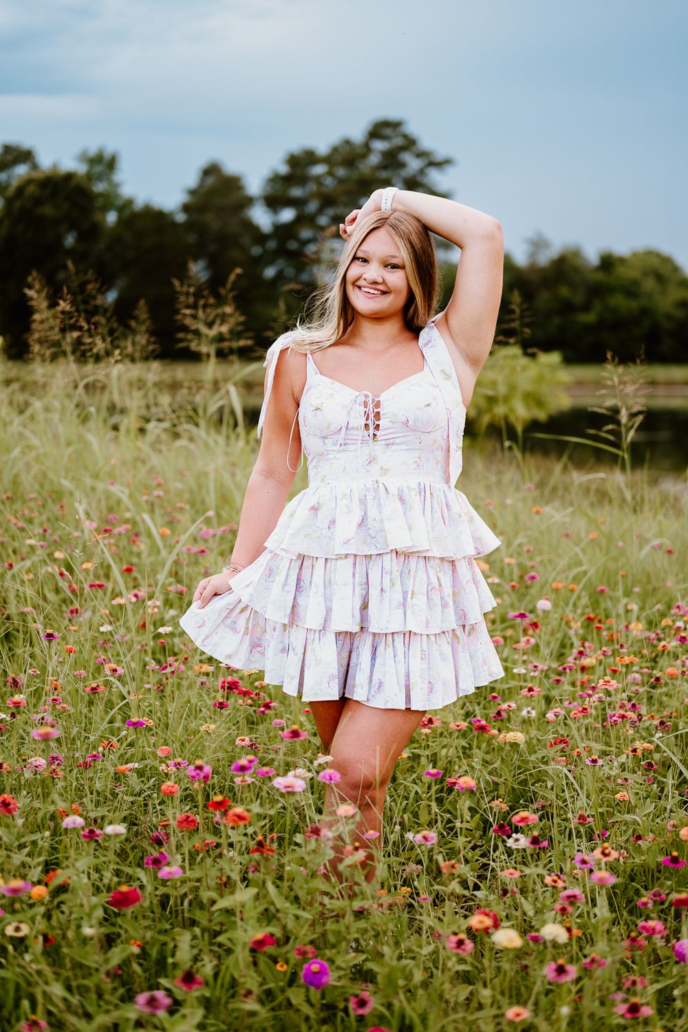 A white ruffle dress stands out against a field of vibrant pink wildflowers on a sunny summer day.